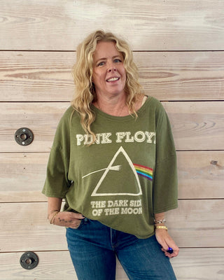 Person wearing a green 'Pink Floyd' t-shirt against a wooden background