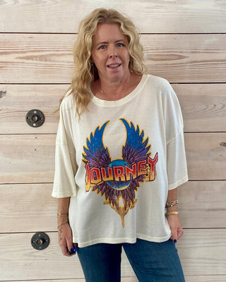 Woman wearing a 'Journey' band t-shirt against a wooden wall.