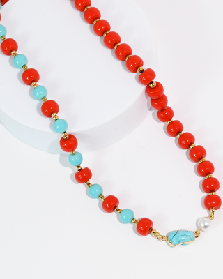 Necklace with red, turquoise, and gold beads on a white background