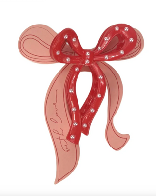 Red bow-shaped hair clip with rhinestones on a white background