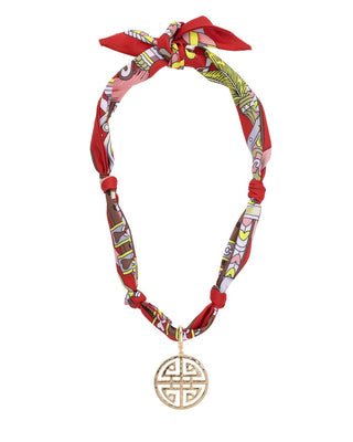 Colorful patterned scarf necklace with a gold pendant on a white background