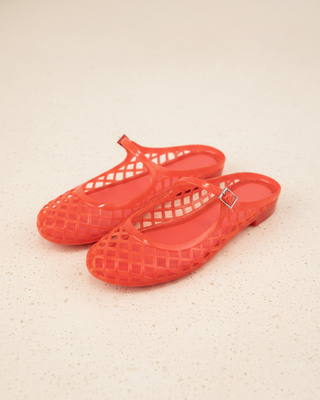 Pair of red jelly sandals on a beige surface