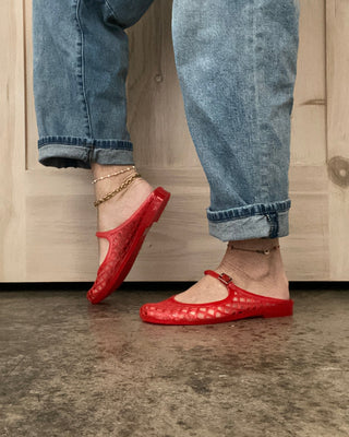 Person wearing red shoes and blue jeans standing on a concrete floor.