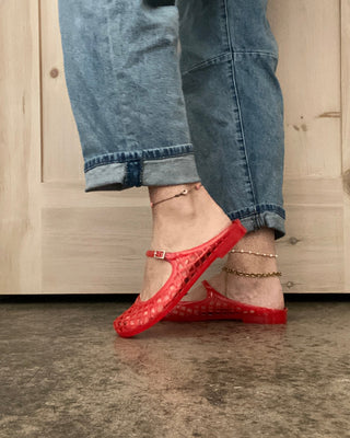 Person wearing red shoes and blue jeans standing on a concrete floor.