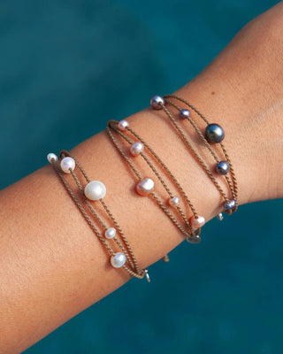 White, blush, and peacock pearl Tula Blue Riptide Drift bracelets stacked on a wrist.