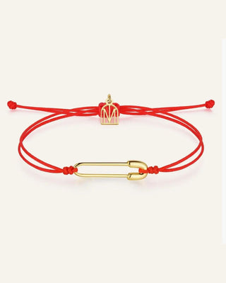 A red adjustable cord bracelet featuring a gold-toned paperclip charm and a small gold-toned MM logo charm, displayed on a light cream background.