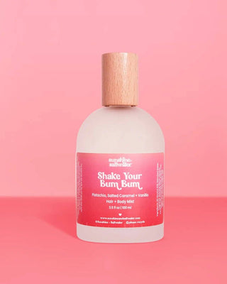 Bottle of 'Shake Your Bum Bum' body mist with a pink label on a pink background