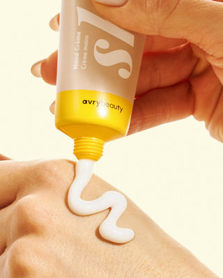 Hand applying cream from a 'avry beauty' tube onto skin