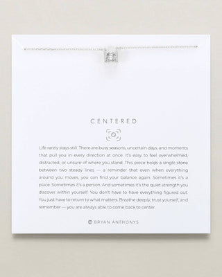 A white card with a delicate silver necklace draped across the top and a printed quote centered under the word "CENTERED." The card includes the brand name Bryan Anthony's at the bottom and is photographed against a light beige background.
