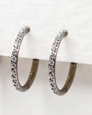 Four silver hoop earrings with small diamonds on a white surface