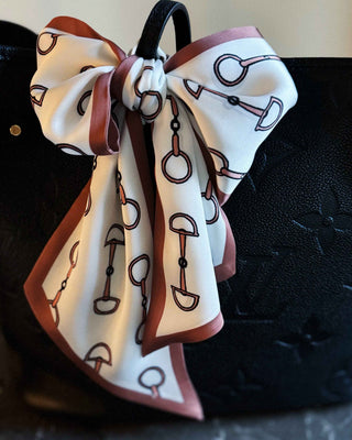 Decorative bow with equestrian pattern on a black leather bag