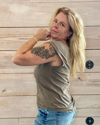 Woman posing against a wooden wall with visible tattoos