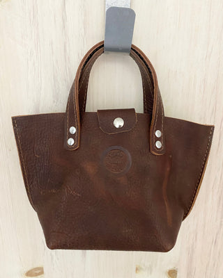 Brown leather handbag with visible brand logo on a light wooden surface