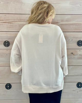 Person wearing a beige sweatshirt against a wooden wall.