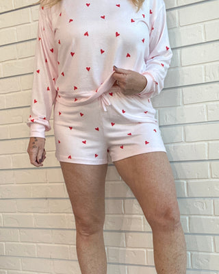 Person wearing a pink outfit with heart patterns on a white tiled floor.