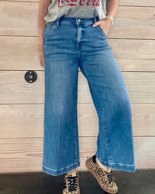 Person wearing a Coca-Cola t-shirt and blue jeans against a wooden background