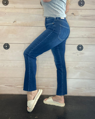 Person wearing blue jeans and a gray top lying on a wooden floor.
