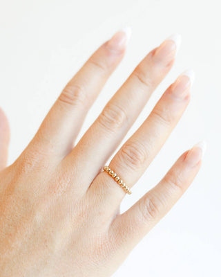 Hand wearing a gold ring on a white background