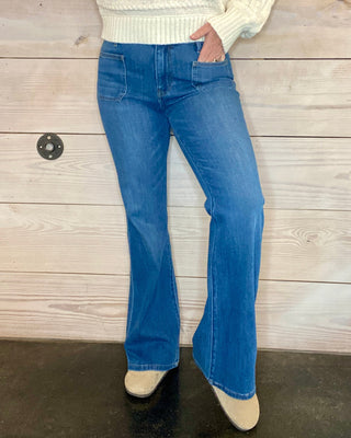 Person wearing a striped sweater and blue jeans against a wooden background
