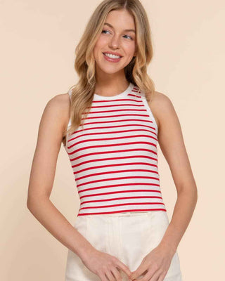 Woman wearing a red and white striped tank top and white shorts on a beige background