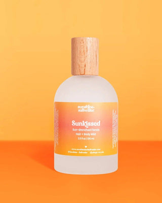 Bottle of 'Sunkissed' hair and body wash with a wooden cap on an orange background