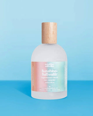 Bottle of Sunshine Saltwater body wash with a wooden cap on a blue background