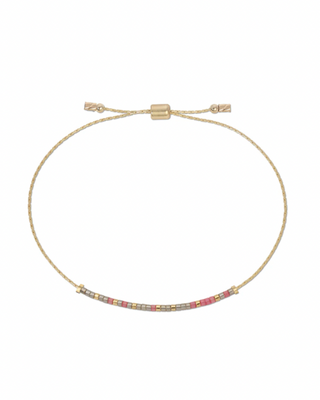 Gold bracelet with small beads that spell our 'survivor' in morse code on a white background.