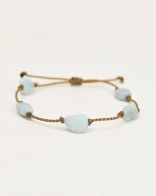 Bracelet with light blue beads and brown cord on a white background