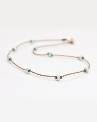 Thin necklace with small blue larimar beads on a white background