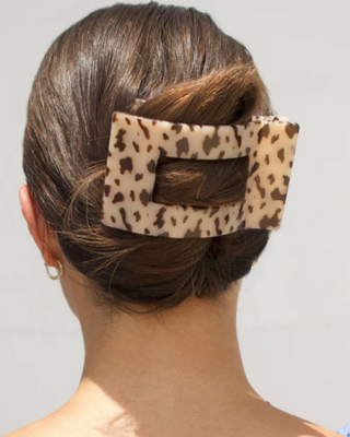 Person with a leopard print hair clip in their bun against a neutral background