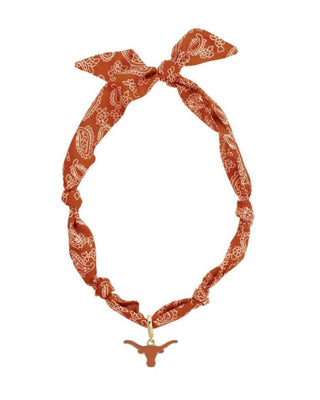 Orange bandana with white patterns and a gold charm on a white background