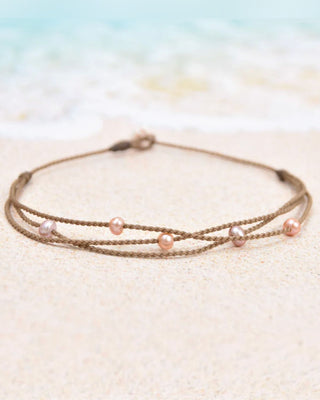 Multistrand bracelet with blush pearls on a sandy background