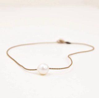Rope necklace with a single pearl on a light background