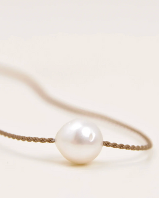 Pearl necklace on rope against a light background