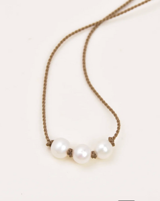 Pearl necklace with brown cord on a white background