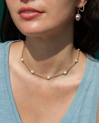 Close-up of a woman wearing a pearl necklace and earrings against a blurred background