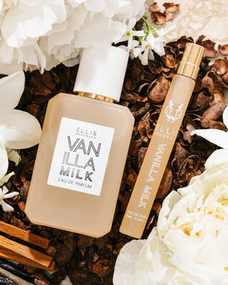 Two perfume bottles labeled 'Vanilla Milk' by Ellis Brooklyn on a background of flowers and vanilla beans.