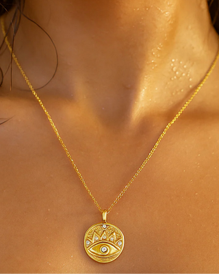 Gold necklace with a decorative pendant on a person's neck