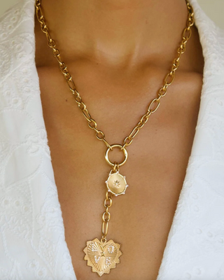 Gold chain necklace with pendant on a person wearing a white outfit