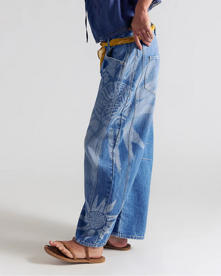 Woman wearing a blue top and tie-dye pants on a white background