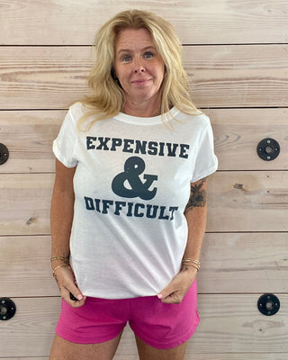 Person wearing a white t-shirt with text standing against a wooden wall.