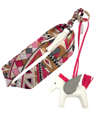 Patterned strap with tassel and white unicorn keychain on a white background