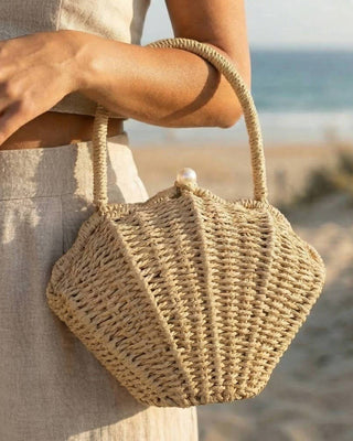 Woven handbag held by a person on a beach