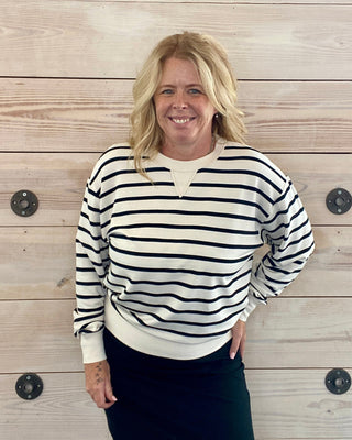 Woman wearing a black and white striped sweater against a wooden wall.