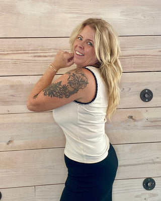 Woman with a tattoo on her arm standing against a wooden wall.